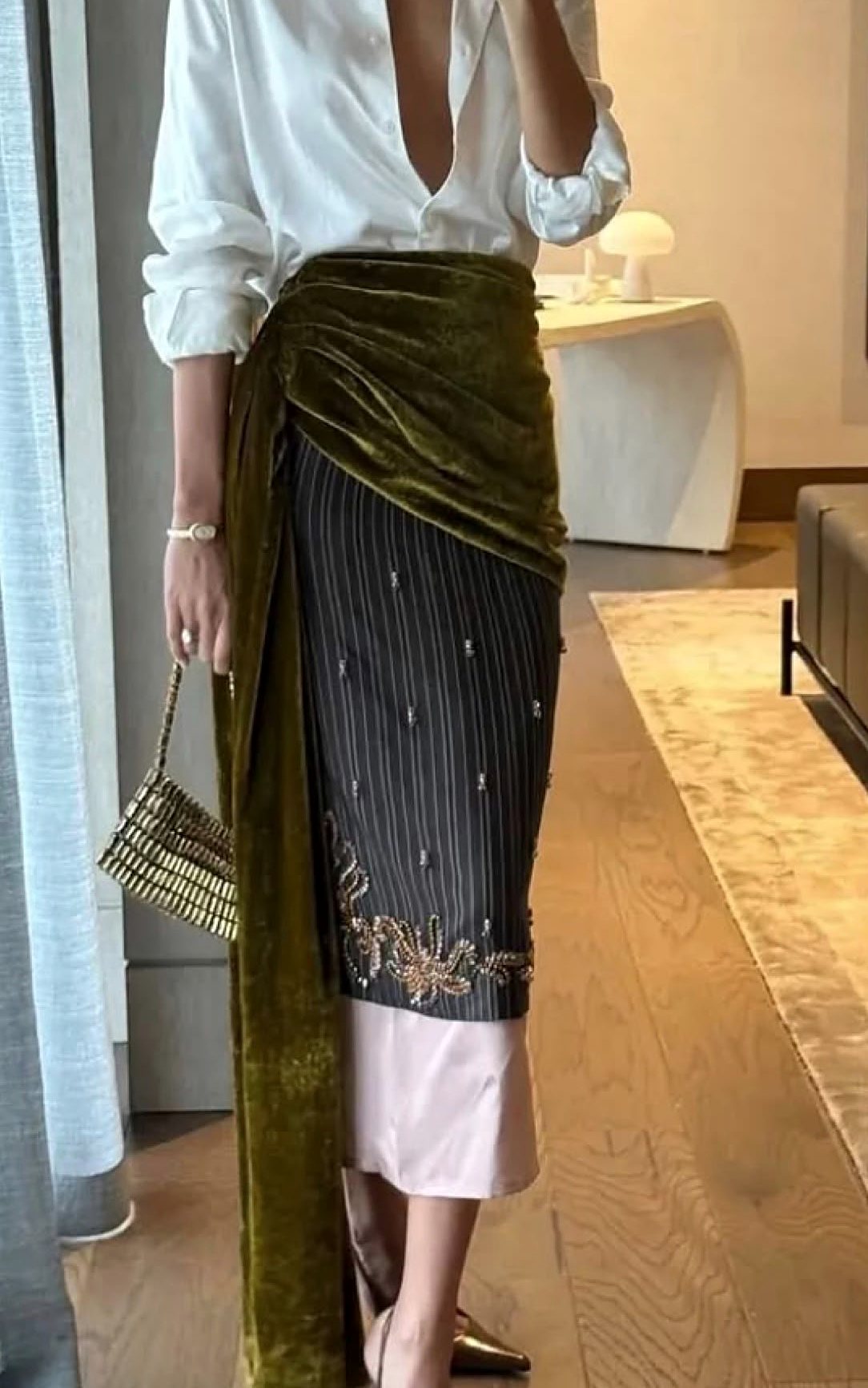 White shirt with an olive velvet sash over an embellished skirt